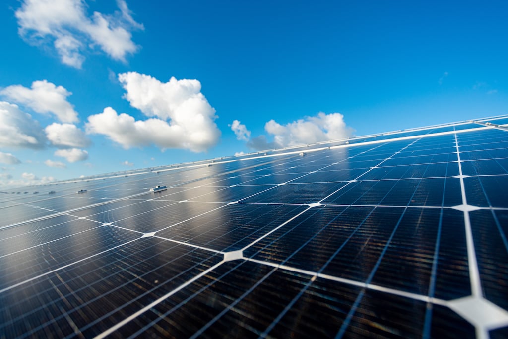 Des panneaux photovoltaïques installés sur une toiture, sous un ciel bleu.
