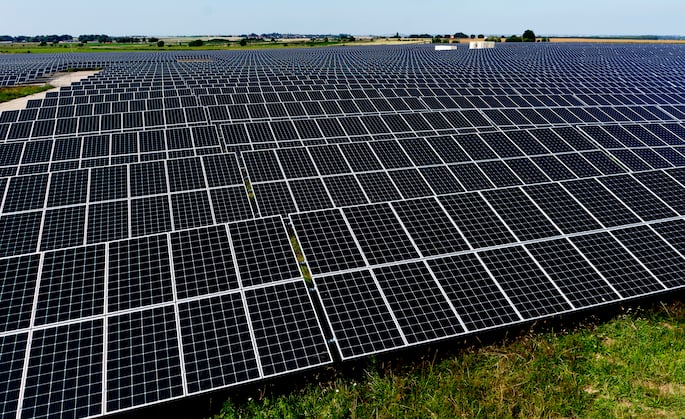 Plusieurs panneaux photovoltaïques posés à même le sol, inutilisable en agriculture, forment une centrale.