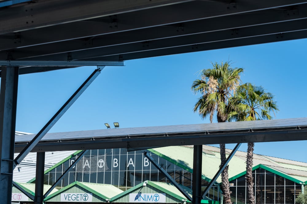 Une ombrière de parking installée sur le parking de l'enseigne Baobab. Vue rapprochée sur les panneaux photovoltaïques qui protègent les voitures.