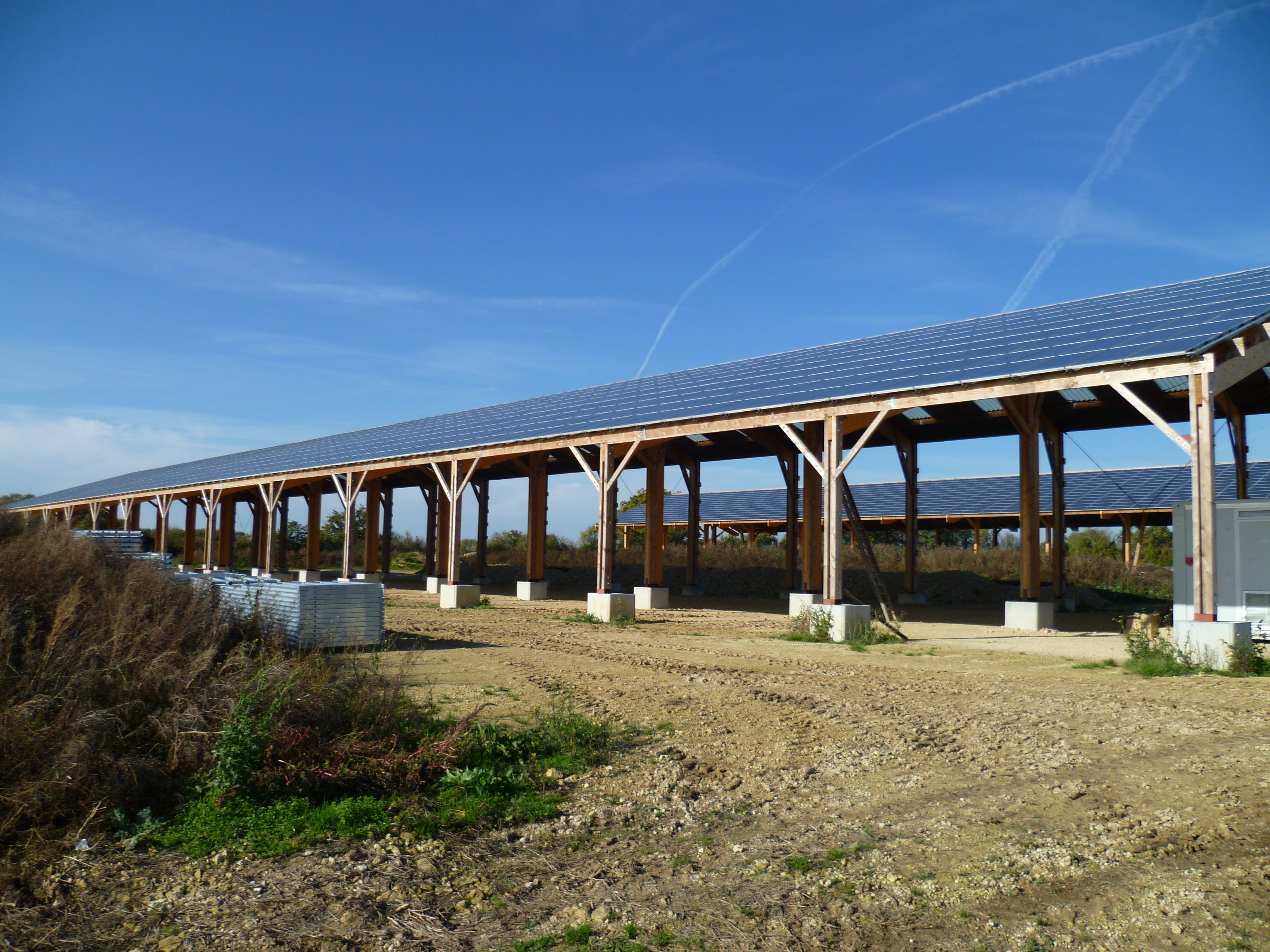 Structure sur-élevées de type bangar ou grange dont les toits sont recouverts de panneaux photovoltaïques.